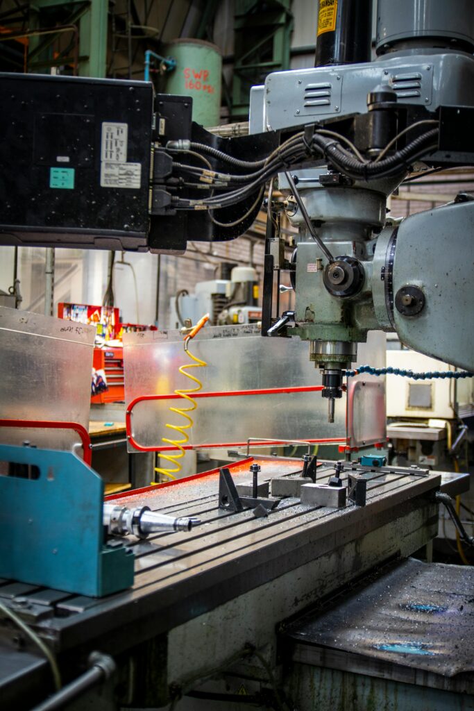 pexels-photo-28929510-28929510 Close-up of an industrial CNC lathe in a bustling machine shop setting, focused on precision metalwork.